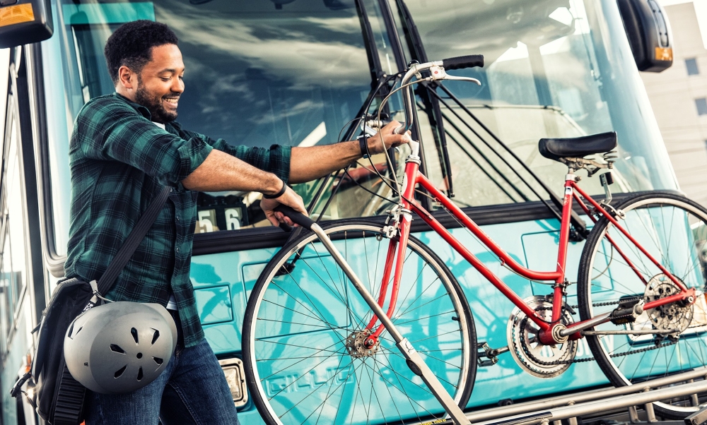 A photo of a man putting his bike on a bus bike rack