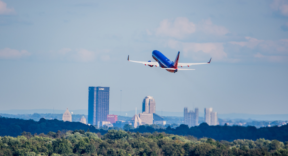 Image of a plane taking off with the city in the background