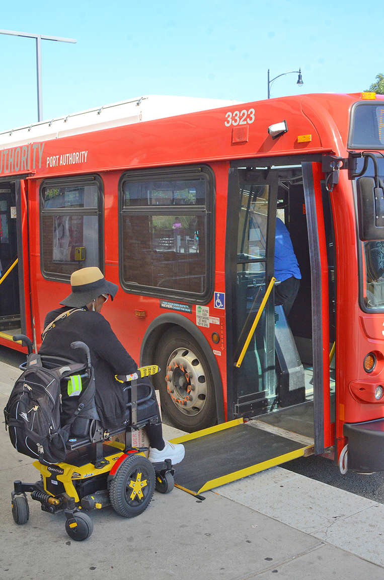 A passenger who uses a mobility device boards the bus via ramp.